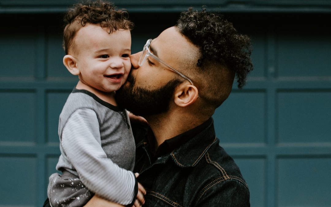 Man holding his son and kissing him on the cheek to represent counseling exercises and parenting with empathy.