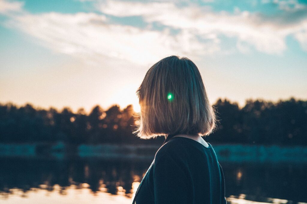 Woman looking at sunset over lake. Representing what to expect from therapy.