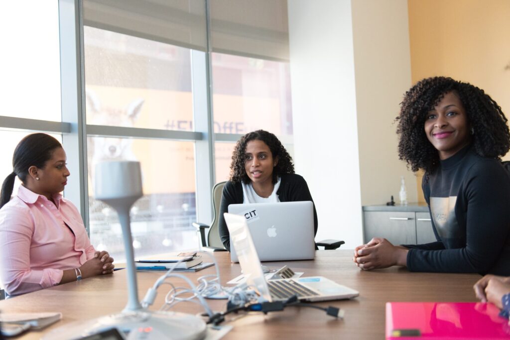 Three women sitting at a table talking to represent group therapy and the benefits of group therapy.