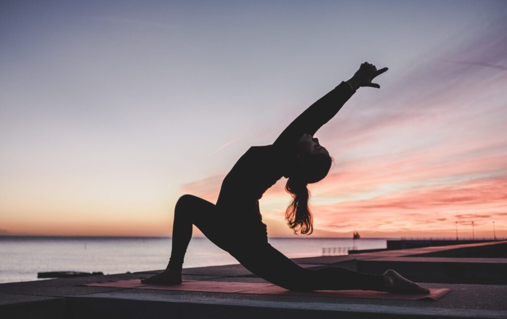 Woman doing yoga outdoors. To represent healthy coping mechanisms.