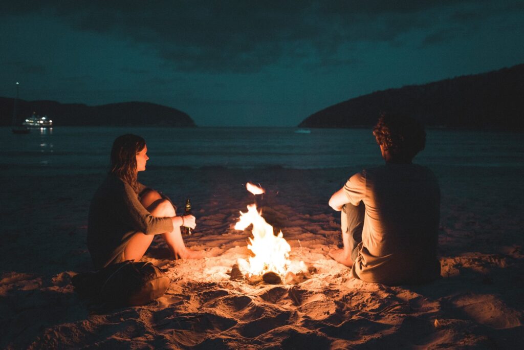 Couple sitting by a bonfire on the ocean to represent couples therapy. 