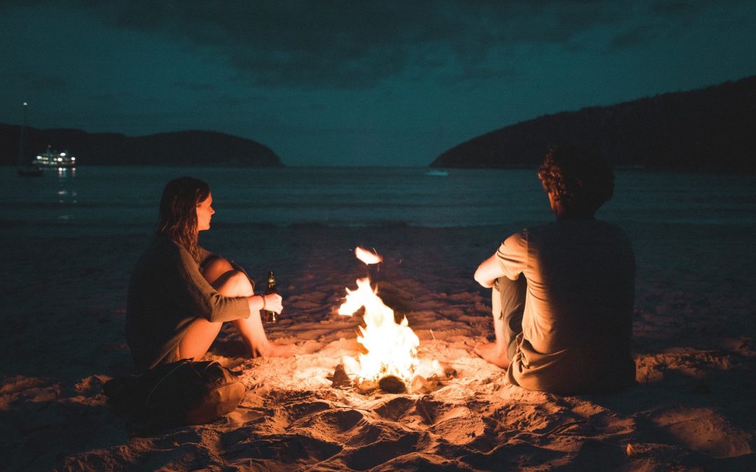 Couple sitting by a bonfire on the ocean to represent couples therapy.