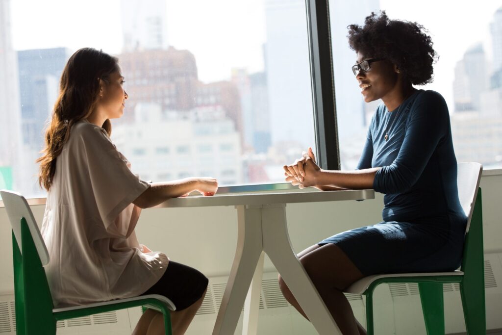 Two women sitting at a table having a conversation.