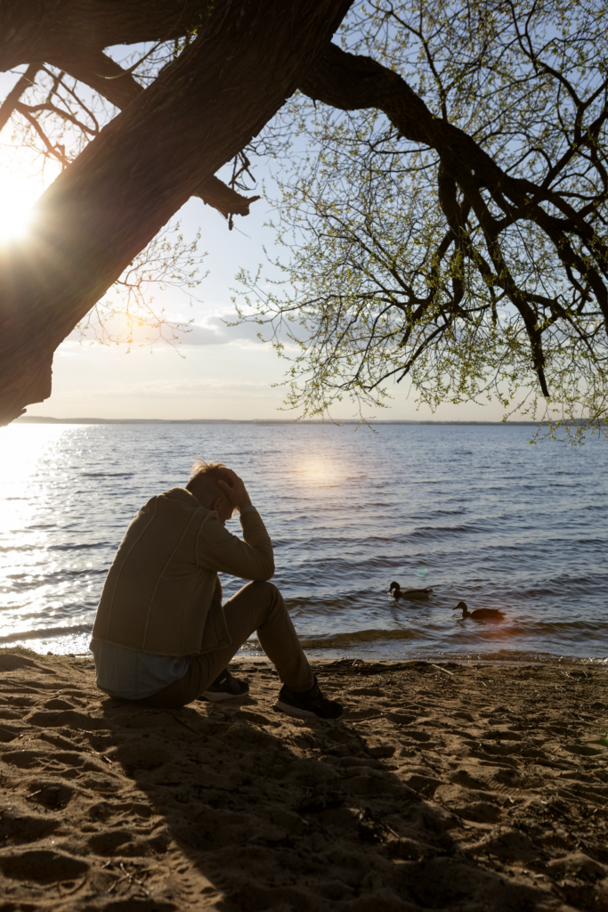 sad person grieving by lake