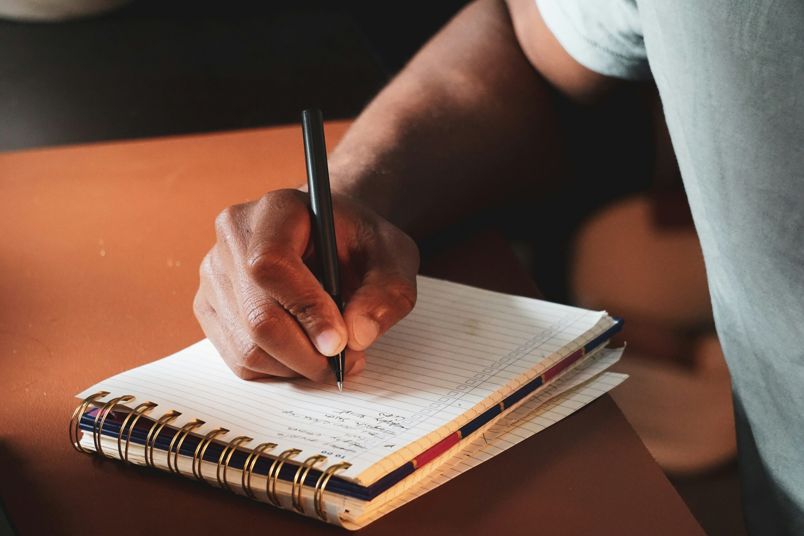 Person writing a to-do list t a home workspace